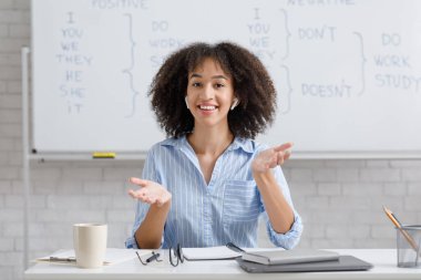 Modern teknoloji, sağlık koronavirüsten korur ve uzaktan evden çalışır. Kablosuz kulaklıklı, İngilizce kurallarını açıklayan neşeli Afro-Amerikan kadını.