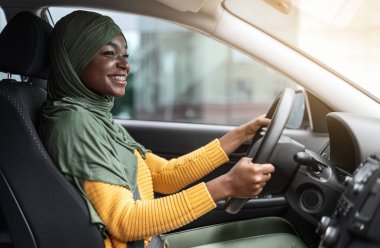 Yolculuk. Yeni arabasında oturan tesettürlü, gülümseyen siyah Arap kadın.