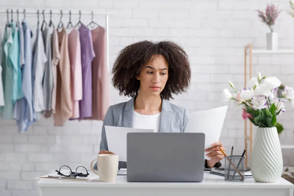 Papierwerk en kleine bedrijven thuis tijdens het coronavirus. Gericht Afrikaans-Amerikaanse vrouw werken met documenten, zitten aan tafel met laptop — Stockfoto