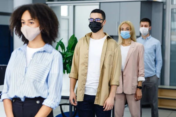 File d'attente pour vérifier la température avant le travail et la nouvelle normale. Travailleurs multiraciaux portant des masques de protection près de l'entrée du bureau pendant l'épidémie de coronavirus — Photo