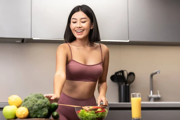 Mulher asiática em Fitwear cozinhar salada para o jantar na cozinha — Fotografia de Stock