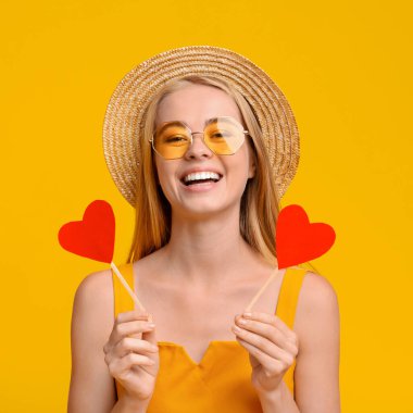 Yaz Aşkı. Neşeli genç kız elinde iki kırmızı kağıt kalp tutuyor.