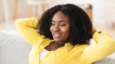 Siyah kadın evinde kanepede dinleniyor.