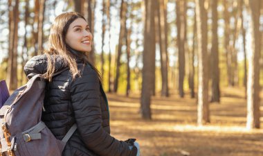 Güzel kız çam ormanında yürürken manzaranın tadını çıkarıyor.