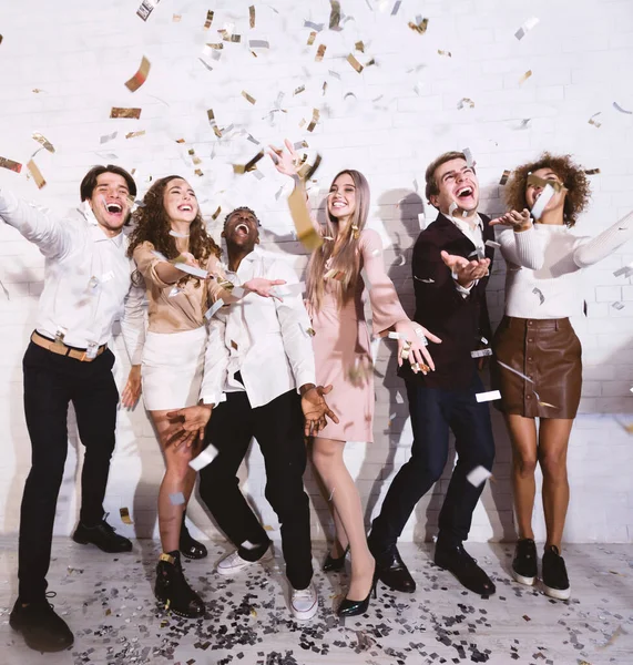 Mladí lidé, kteří mají večírek s pádem Confetti baví Indoors — Stock fotografie