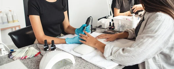 Master in rubber handschoenen doen hardware manicure voor vrouw in interieur van schoonheidssalon op tafel met apparatuur na covid-19 quarantaine — Stockfoto