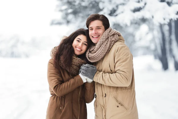 Glad flickvän och pojkvän som håller händerna stående i vinterskogen — Stockfoto