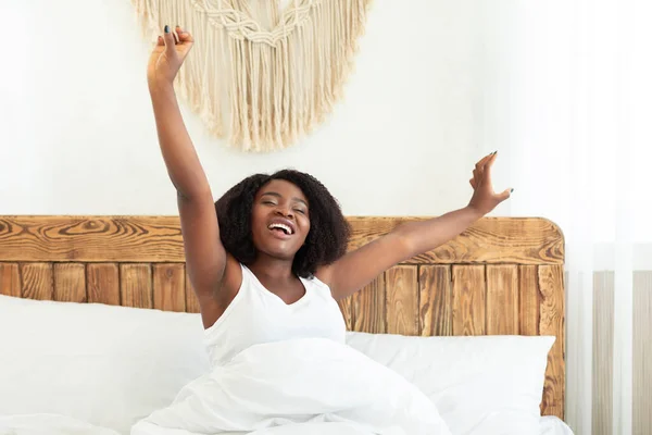 Young happy black lady model stretching sitting in bed — Stock Photo, Image