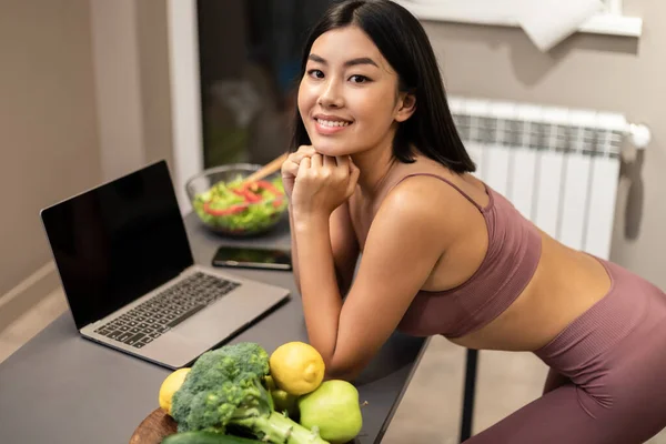 Slim Chinese Lady Using Laptop Searching Recipes Cooking In Kitchen