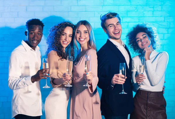 Glada studenter som håller glasögonen med Champagne stående mot vägg inomhus — Stockfoto