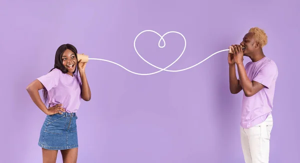Afroamerikaner teilt Gefühle mit seiner Freundin durch Blechdose Telefon auf fliederfarbenem Hintergrund — Stockfoto