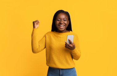 Büyük Galibiyet. Neşeli Siyahi Kadın Akıllı Telefonla Başarıyı Kutluyor