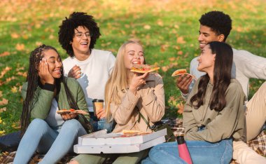 Sarışın kız arkadaşlarıyla piknik yapıyor, lezzetli pizzanın tadını çıkarıyor.