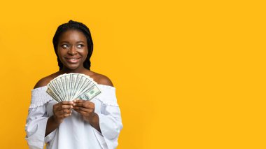 Pensive Brunette Woman Holding Money Dollar Cash And Looking At Copy Space On Yellow Background, Thinking About Investment Plans, Celebrating Financial Success, Received Bonus, Panorama clipart