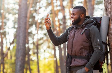 Akıllı telefon tutan mutlu siyah adam, sonunda ormanda GPS 'i var.
