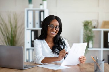 Ofisteki evraklarla çalışan güzel siyahi iş kadını.