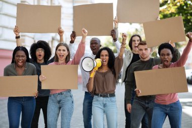 Göstericilerden oluşan megafonlu genç bir bayan.