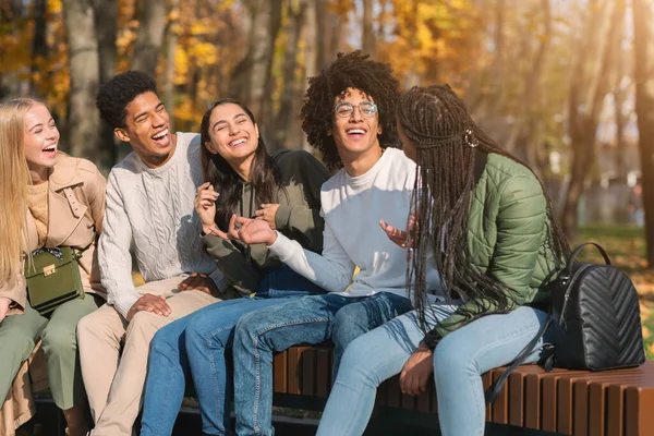 Подростки веселятся в общественном парке, сидят на скамейке, разговаривают — стоковое фото