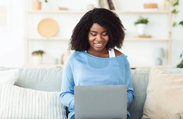 Mulher negra sentada no sofá e trabalhando no pc — Fotografia de Stock