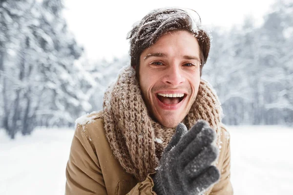 Hombre feliz frotando las manos sonriendo de pie en el bosque nevado —  Fotos de Stock
