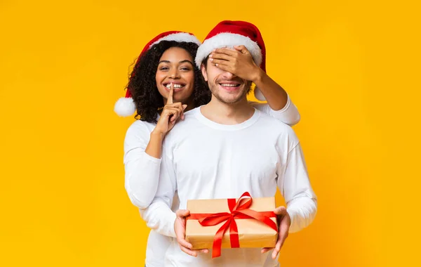 Black woman making surprise to boyfriend and giving him Christmas present — Stock Photo, Image