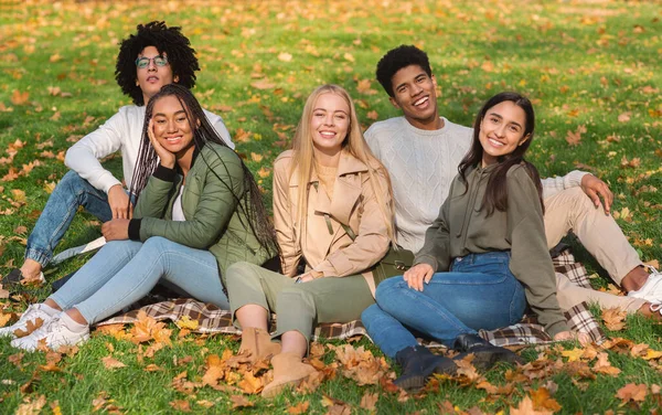 Amigos adolescentes despreocupados sentados en el suelo en el parque público —  Fotos de Stock