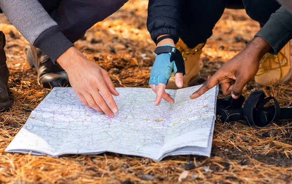 Backpackers ukazuje na mapu, hledá jejich umístění v lese — Stock fotografie
