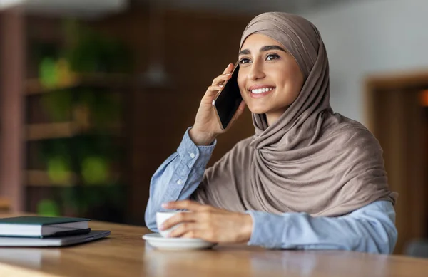 Dame musulmane souriante parlant au téléphone tout en se reposant au café — Photo