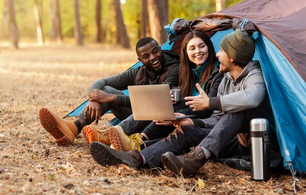 Cheerful friends discussing hiking route, using laptop — Stock Photo, Image