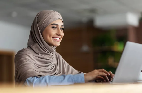 Vidám arab hölgy hidzsáb szabadúszó dolgozik online cafe — Stock Fotó