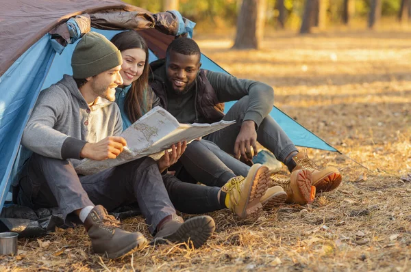 Amis randonneurs regardant la carte tout en se reposant dans la tente — Photo