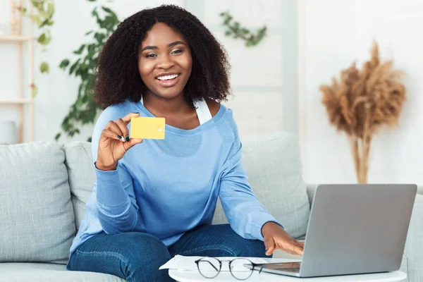 Black woman using laptop and showing credit card