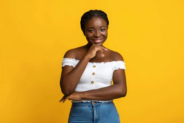 Portret van aantrekkelijke Millennial zwarte dame glimlachen bij de camera, aanraken van kin — Stockfoto