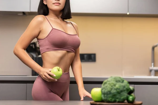 Mulher magra dieta segurando maçã de pé na cozinha interior, cortada — Fotografia de Stock