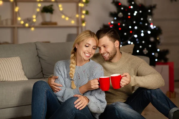 Happy husband and wife cheering with cocoa mugs at home — ストック写真