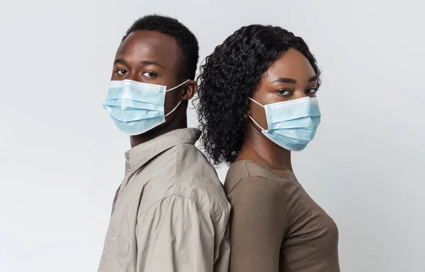 Africano casal americano vestindo máscaras médicas protetoras de volta para trás — Fotografia de Stock