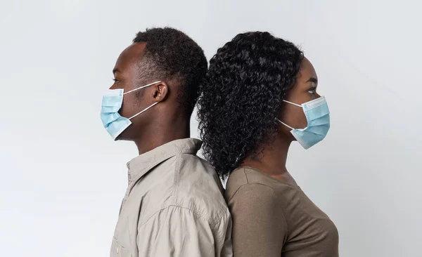 Casal preto vestindo máscaras protetoras de pé de volta para trás — Fotografia de Stock