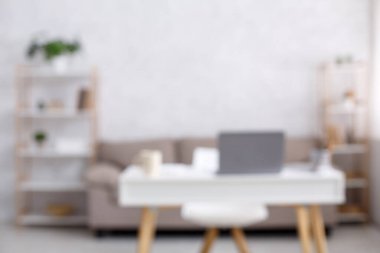 Merkez ofis, uzaktan çalışma alanı. COVID-19 salgını sırasında oturma odasının içinde dizüstü bilgisayarı ve fincanı olan kanepe, sandalye ve masa.