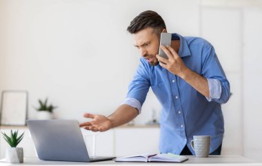 İşteki sorunlar. Sinirli iş adamı cep telefonuyla konuşuyor, bilgisayarla ilgili sorunları var.