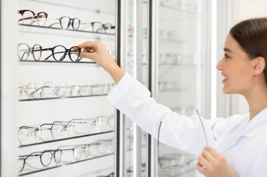 Gösterge rafında çeşitli gözlük gösteren kadın satıcı