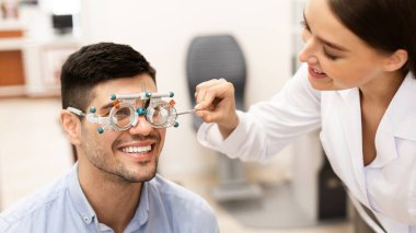 Optometrist hasta vizyonunu deneme çerçevesi ile kontrol ediyor
