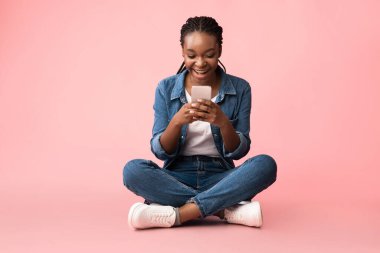 Pembe Arkaplanda Oturan Cep Telefonu Mesajlı Heyecanlı Afrikalı Kadın