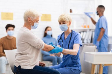 Coronavirus aşısı olan Kıdemli Kadın Salonda Doktorla Oturuyor