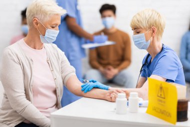 Kıdemli Bayan Covid-19 Aşı Alıyor. Evde hemşireyle oturuyor.