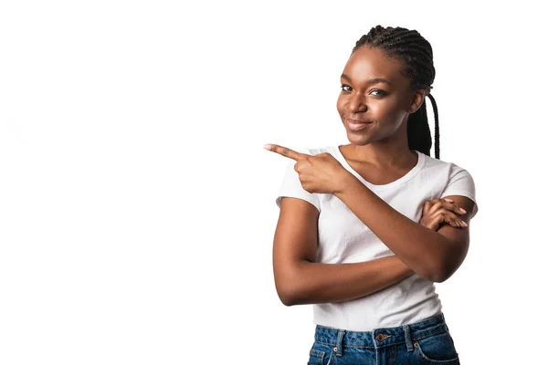 Молодая черная леди указывает пальцем в сторону, стоя на белом фоне — стоковое фото
