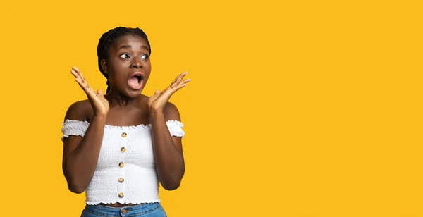 Удивительное предложение. Потрясенная африканская женщина смотрит на копировальное пространство на жёлтом фоне — стоковое фото