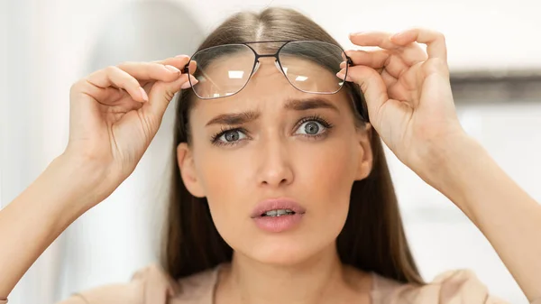 Porträtt av förvirrad ung kvinna tittar genom glasögon — Stockfoto