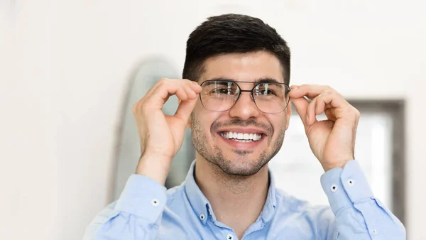 Портрет усміхненого красивого чоловіка, який пробує на окулярах — стокове фото