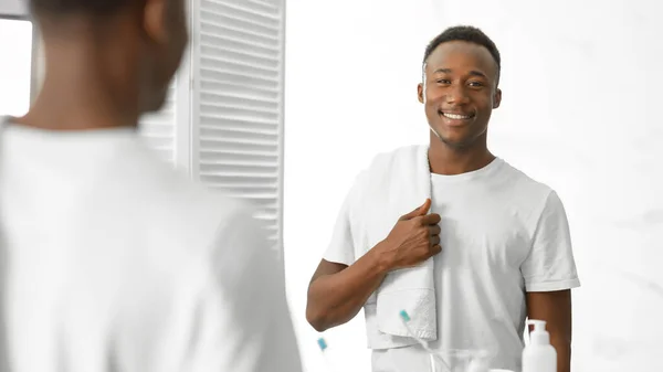 Guapo joven negro hombre de pie sosteniendo la toalla en baño moderno —  Fotos de Stock