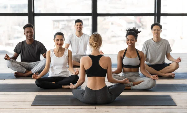 Wellness koncepció. Női jógaoktató Csoportos lecke a fiatal multiracionális emberekkel — Stock Fotó
